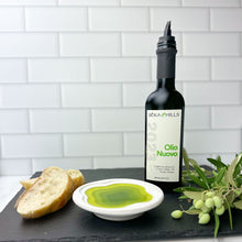 Bottle of Seka Hills Olio Nuovo on a black slate board with bowl of olive oil and bread slices